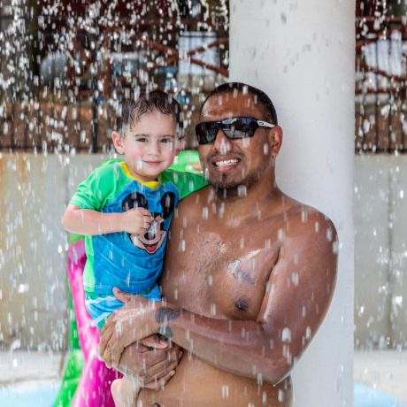 man and child smiling in water play area